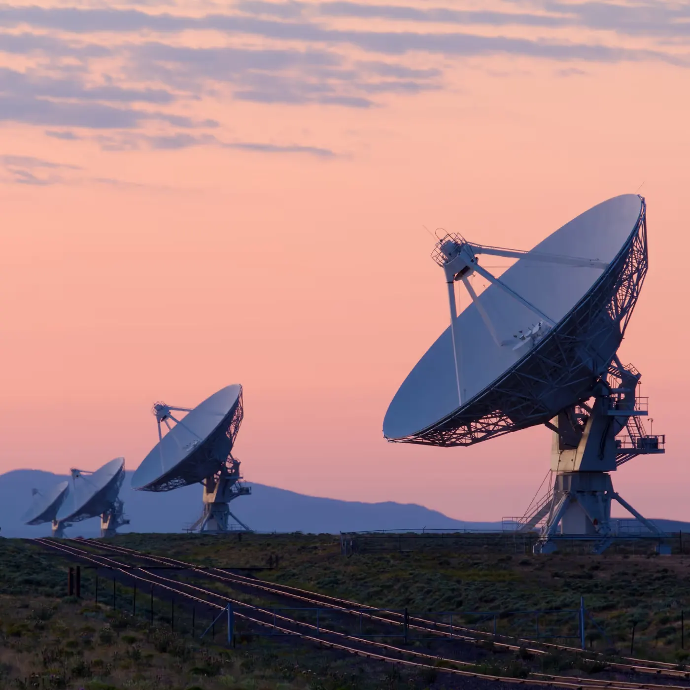 Row of satellite dishes at dusk — telecommunications infrastructure secured by facial authentication